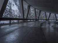 people walk under an overpass in the rain on a mountaintop road with snow