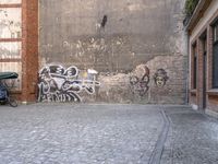 there's a person standing in the alley looking at graffiti on the wall with a bike parked