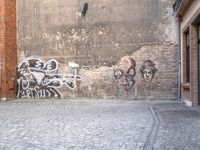 there's a person standing in the alley looking at graffiti on the wall with a bike parked