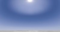 a person is standing on the desert looking up at a bright blue sky and the sun behind them