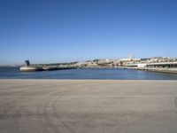 a person flying a kite near a city on a sunny day in spain, from an empty parking lot