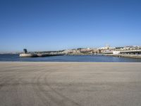 a person flying a kite near a city on a sunny day in spain, from an empty parking lot