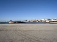 a person flying a kite near a city on a sunny day in spain, from an empty parking lot