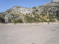 the shadow of a person in a parking lot, looking at a rock wall with a tree on top