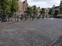 a person riding a bicycle down a brick road in front of other buildings and bicycles