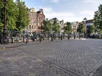 a person riding a bicycle down a brick road in front of other buildings and bicycles