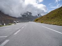 a person on an orange bike riding down a mountain road with the clouds coming over the mountains behind them