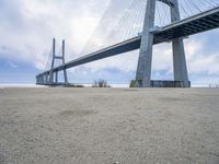 a person is riding their bike under a bridge on the beach in the background are buildings and water