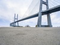 a person is riding their bike under a bridge on the beach in the background are buildings and water