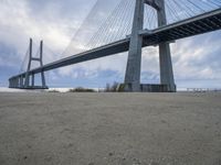 a person is riding their bike under a bridge on the beach in the background are buildings and water