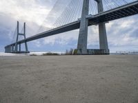 a person is riding their bike under a bridge on the beach in the background are buildings and water