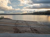 a person is sitting in a row on a dock by the river in front of an overcast sky