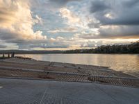 a person is sitting in a row on a dock by the river in front of an overcast sky