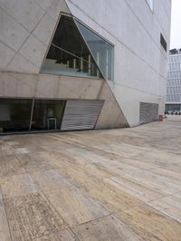 a person on a skateboard on a wooden ground near a building with windows and stairs