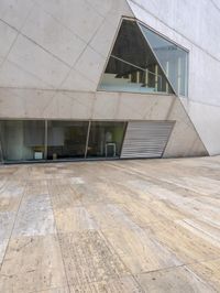 a person on a skateboard on a wooden ground near a building with windows and stairs