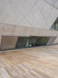 a person on a skateboard on a wooden ground near a building with windows and stairs