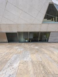 a person on a skateboard on a wooden ground near a building with windows and stairs