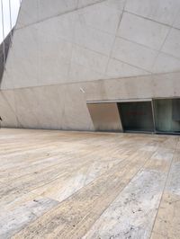 a person on a skateboard on a wooden ground near a building with windows and stairs