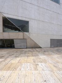 a person on a skateboard on a wooden ground near a building with windows and stairs