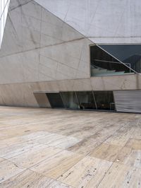 a person on a skateboard on a wooden ground near a building with windows and stairs