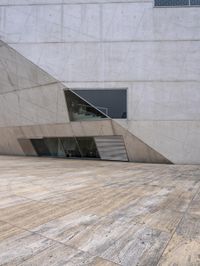 a person on a skateboard on a wooden ground near a building with windows and stairs