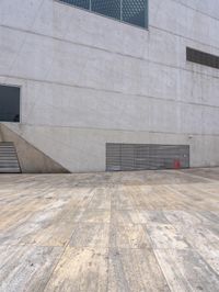 a person on a skateboard on a wooden ground near a building with windows and stairs