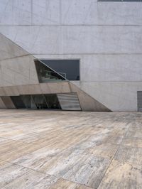 a person on a skateboard on a wooden ground near a building with windows and stairs