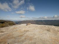 a person standing on the top of a mountain, while he looks at the view