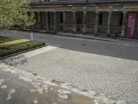 a person holding an umbrella walks in front of a building that has columns and pillars