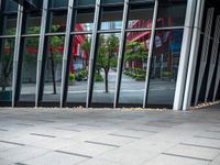 a person holding an umbrella walks in front of a glass building with a clock on it