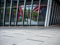 a person holding an umbrella walks in front of a glass building with a clock on it