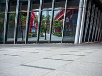 a person holding an umbrella walks in front of a glass building with a clock on it