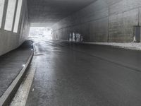 person with umbrella walking on road next to a building underpasses underpass with street light