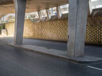 a person with an umbrella walks down a street under a bridge where there is only a few people