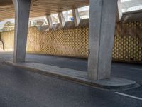 a person with an umbrella walks down a street under a bridge where there is only a few people