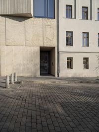 a person with a suitcase walking across an outside courtyard in front of a building,