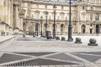 a person with umbrella walks on the sidewalk near the royal palace in paris, france