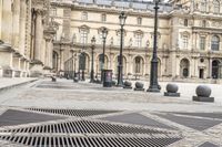 a person with umbrella walks on the sidewalk near the royal palace in paris, france