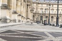 a person with umbrella walks on the sidewalk near the royal palace in paris, france