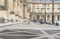 a person with umbrella walks on the sidewalk near the royal palace in paris, france