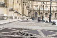 a person with umbrella walks on the sidewalk near the royal palace in paris, france