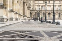 a person with umbrella walks on the sidewalk near the royal palace in paris, france