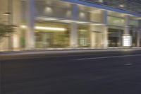 a woman on a city bike driving by a building at night time on a street