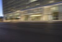 a woman on a city bike driving by a building at night time on a street