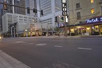 a city street lined with tall buildings in the evening hours with traffic passing by and oncoming, cars drive past and driving in front
