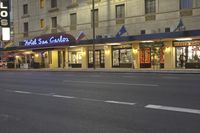 a city street lined with tall buildings in the evening hours with traffic passing by and oncoming, cars drive past and driving in front