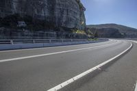 the paved highway stretches into the mountain on its own side and is close to a cliff