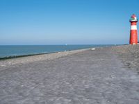 an ocean shore with a lighthouse and people in boats on the water at sea side