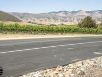 a rural view with a road and fields in the background and mountains in the distance