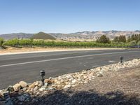 a rural view with a road and fields in the background and mountains in the distance